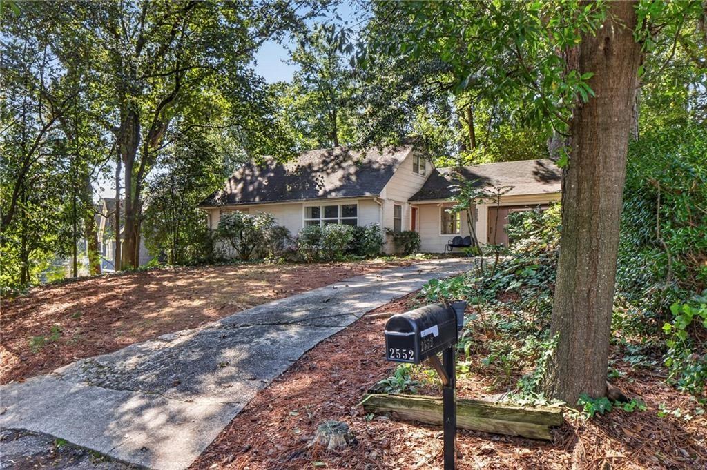 House on a wooded lot with a curving driveway and mailbox marked 2552.