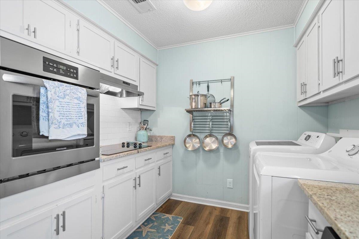 Laundry room with white cabinets, stainless oven, and two washing machines.