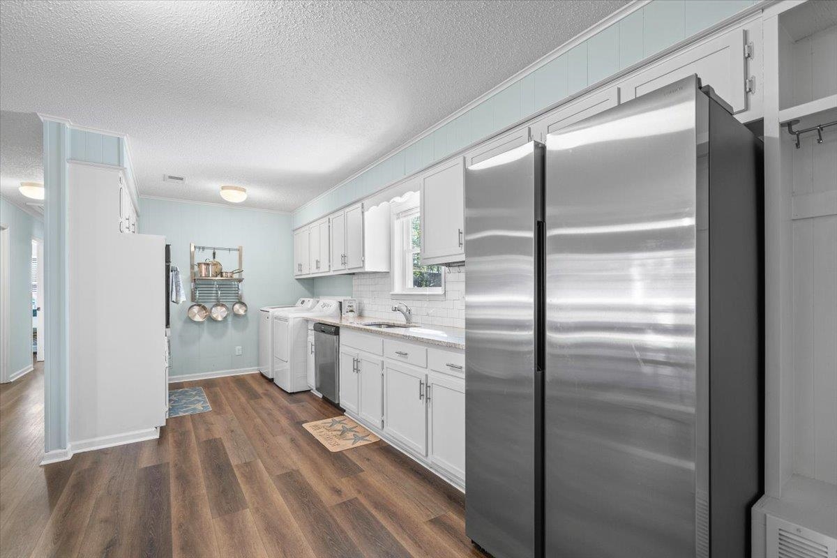 Kitchen with white cabinets, stainless steel appliances, and dark wood flooring.
