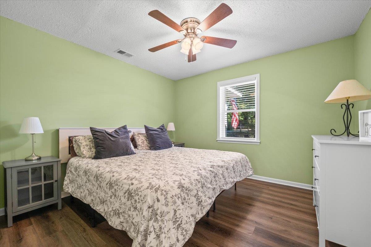 Bedroom with a floral-covered bed, pale green walls, and a ceiling fan.