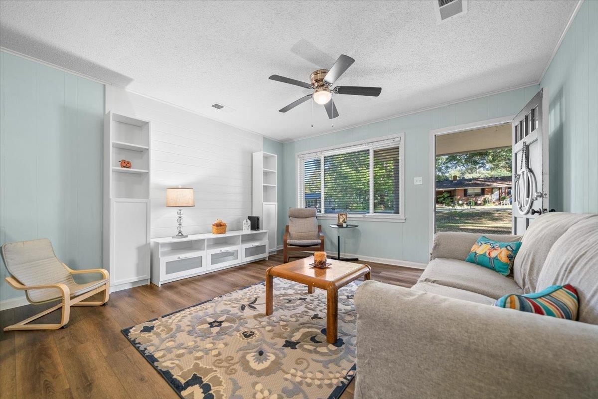 Living room with pale blue walls, built-in shelving, a ceiling fan, and a large window.