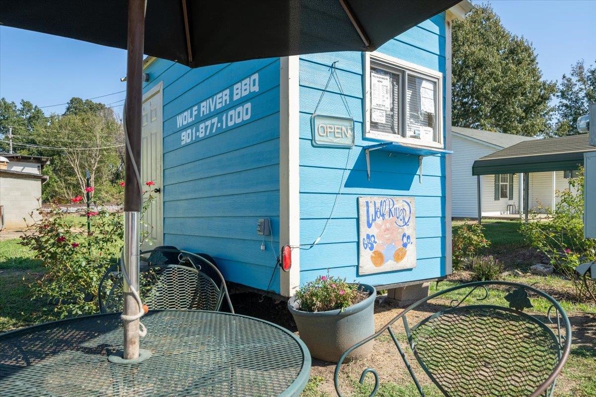 Blue Wolf River BBQ stand with an open sign and outdoor patio seating.