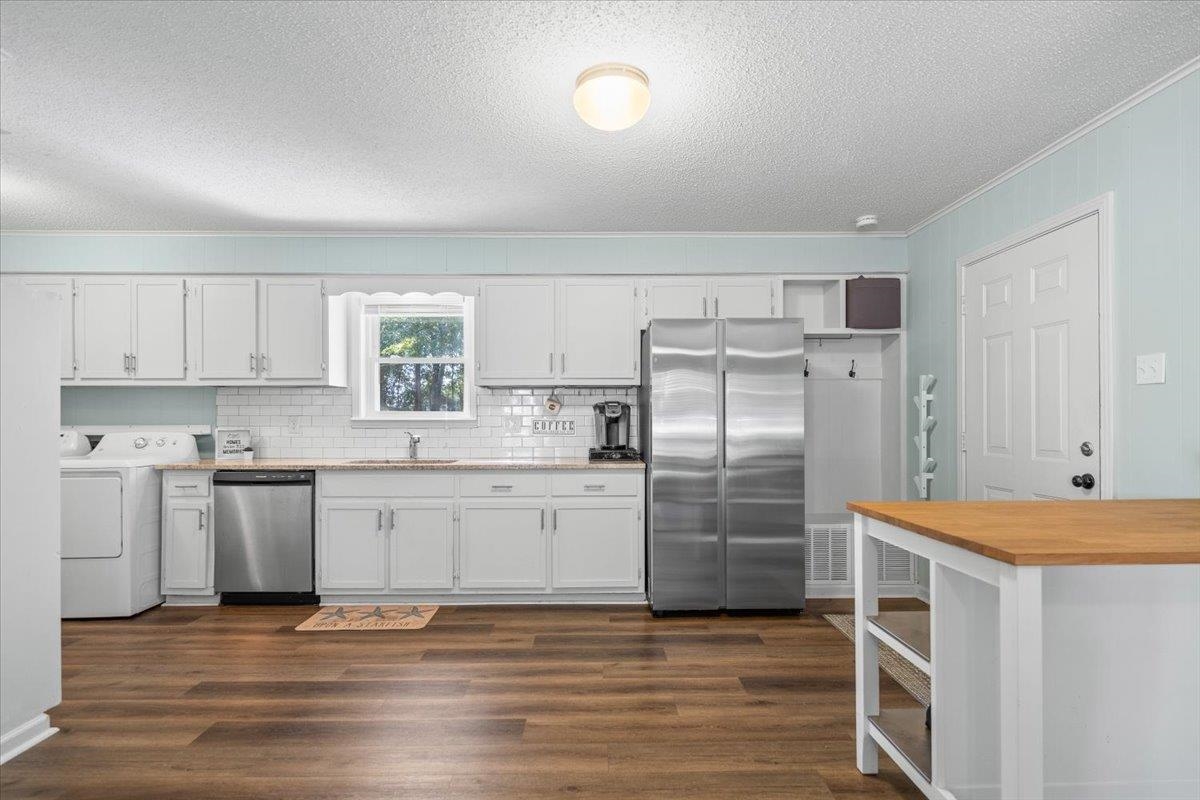 Kitchen with white cabinets, stainless steel appliances, and a wood-topped island.