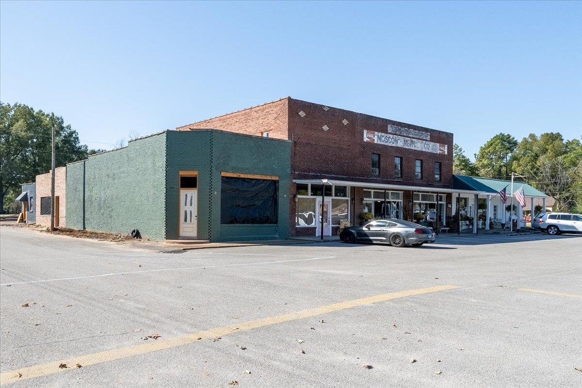 Brick downtown commercial storefront with a green-painted facade and parked cars along the street.