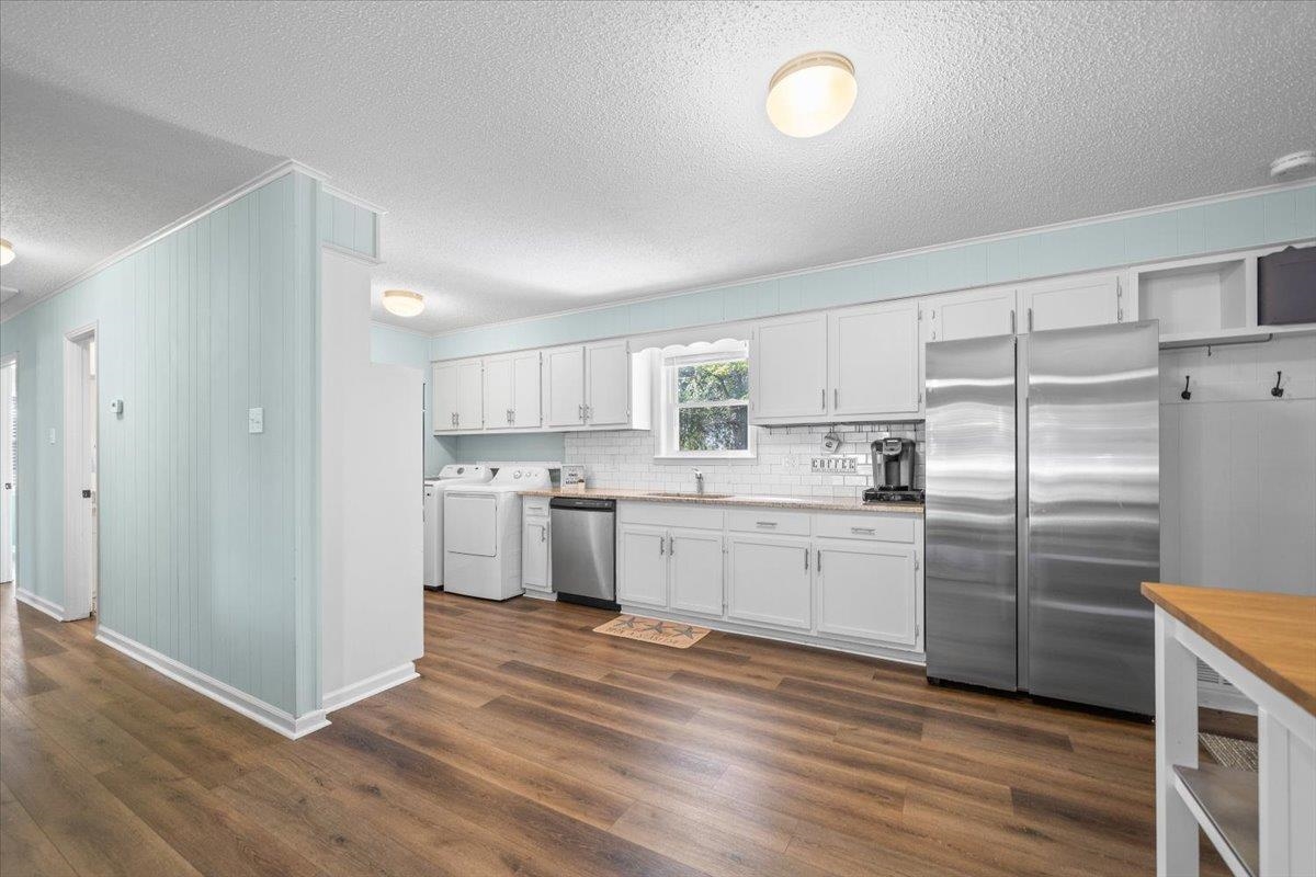 Kitchen with white cabinets, stainless steel refrigerators, and wood-look flooring.