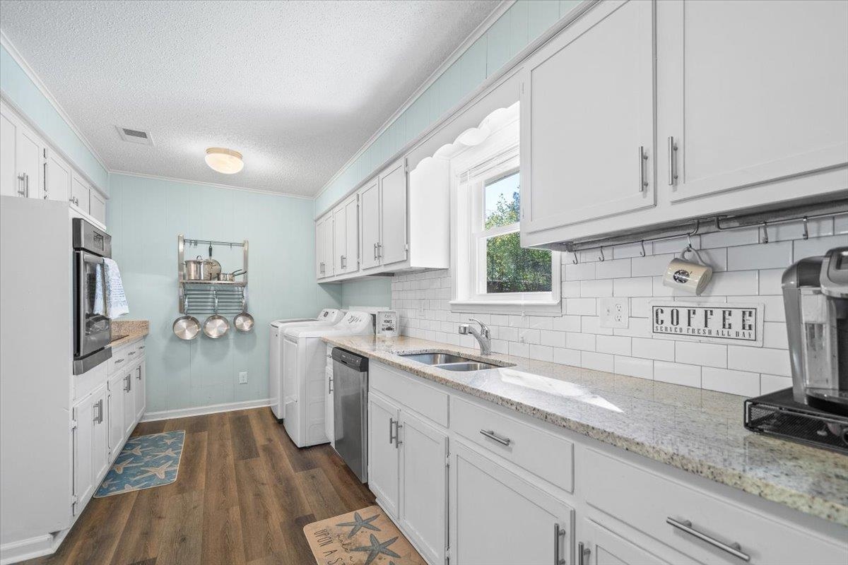 Bright kitchen with white cabinets, subway tile backsplash, and laundry appliances.