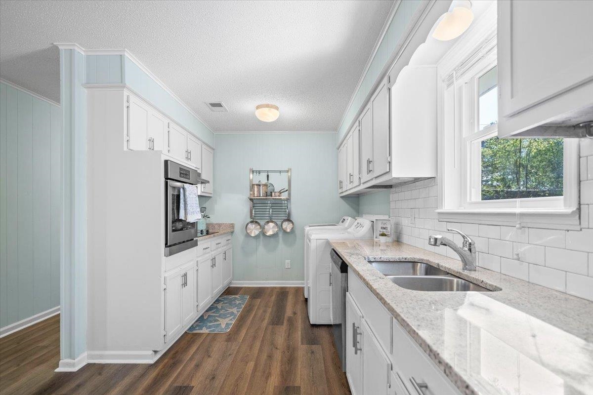 Kitchen with white cabinets, pale blue walls, stainless appliances, and a double sink.