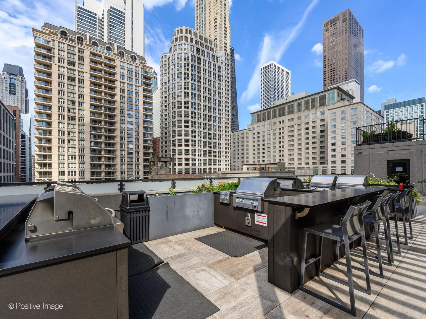 Rooftop deck with built-in grills and bar seating overlooking downtown towers.