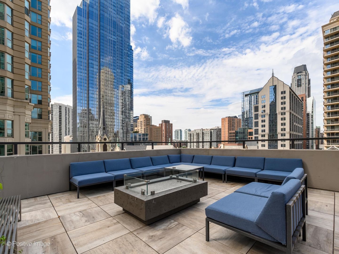 Rooftop terrace with blue sectional seating and fire table overlooking Chicago’s high-rise skyline.