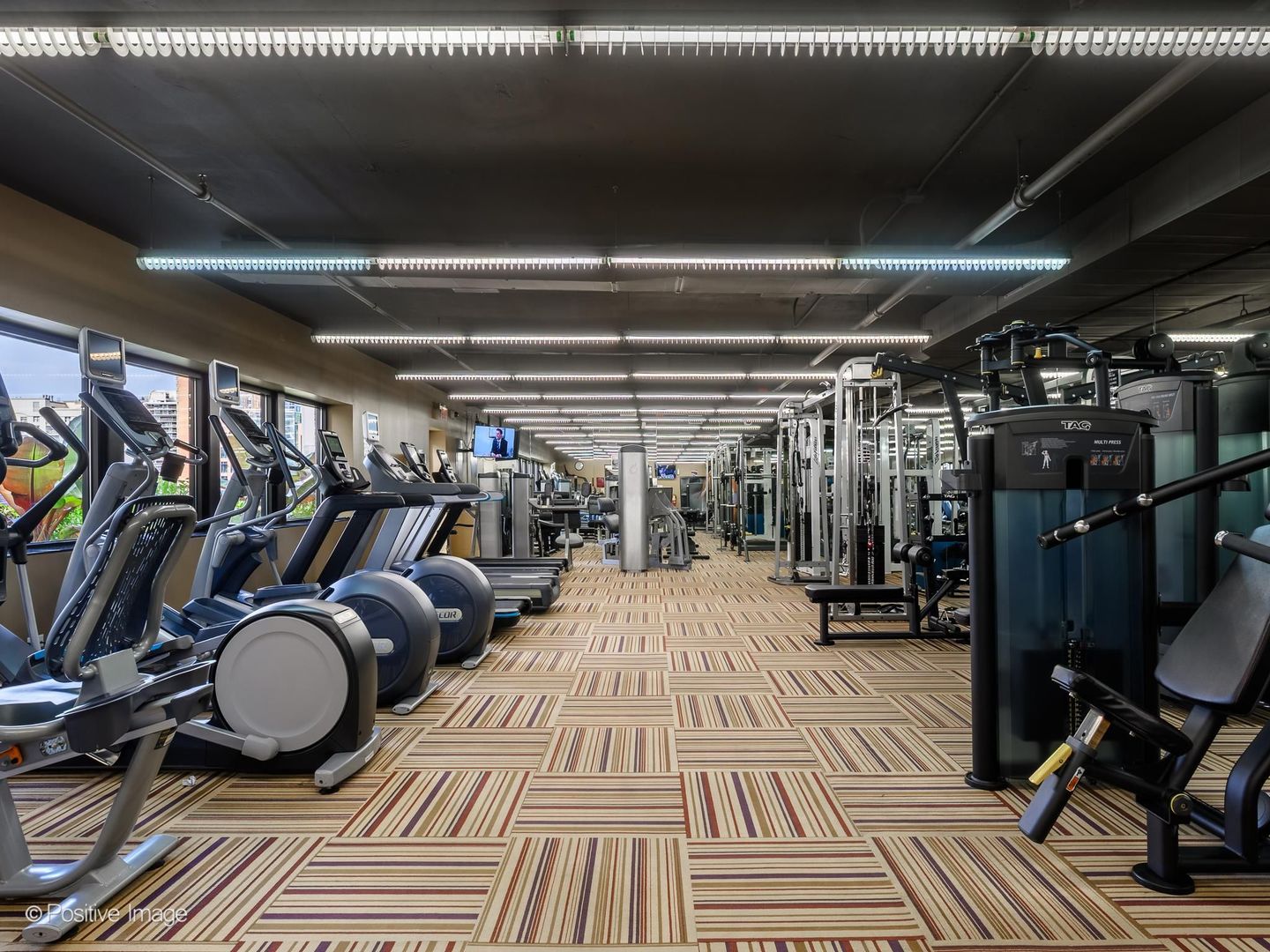 Fitness center with treadmills by the windows and weight machines across the room.