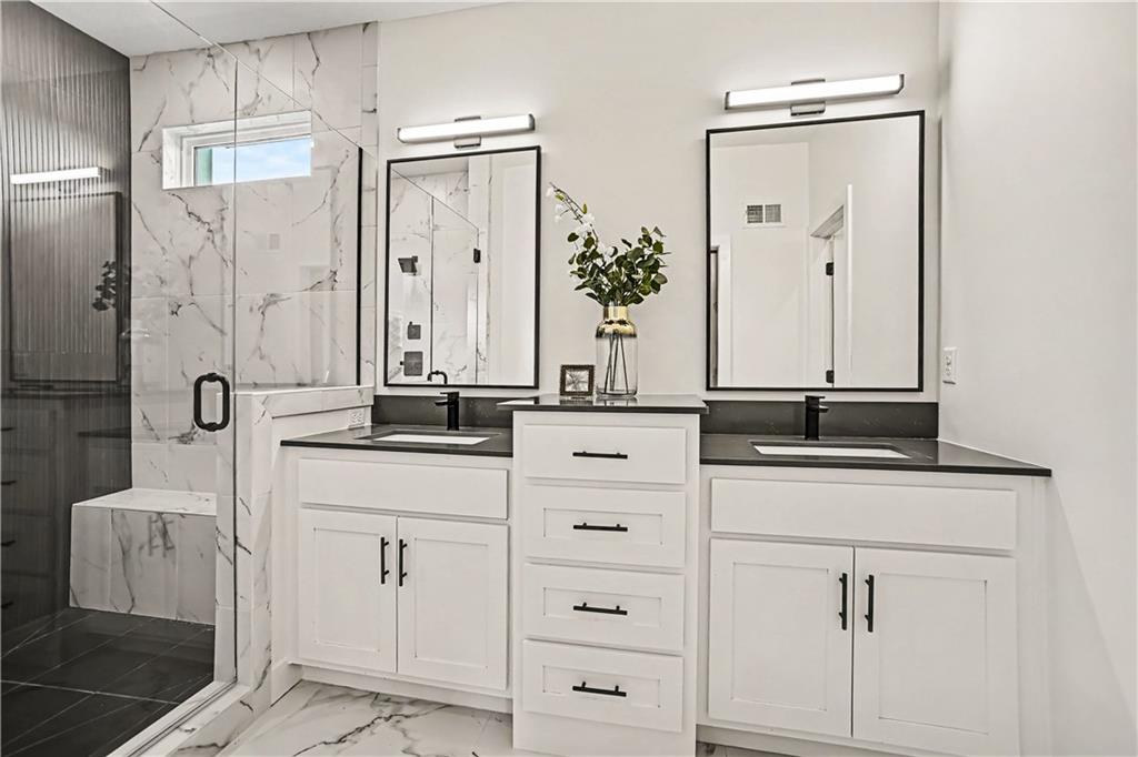 Modern bathroom with a white double vanity and marble-look glass-enclosed shower.