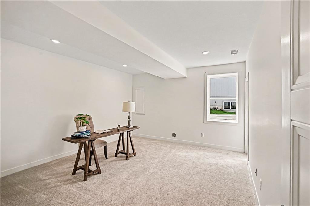 Carpeted home office with a desk, chair, lamp, and window.