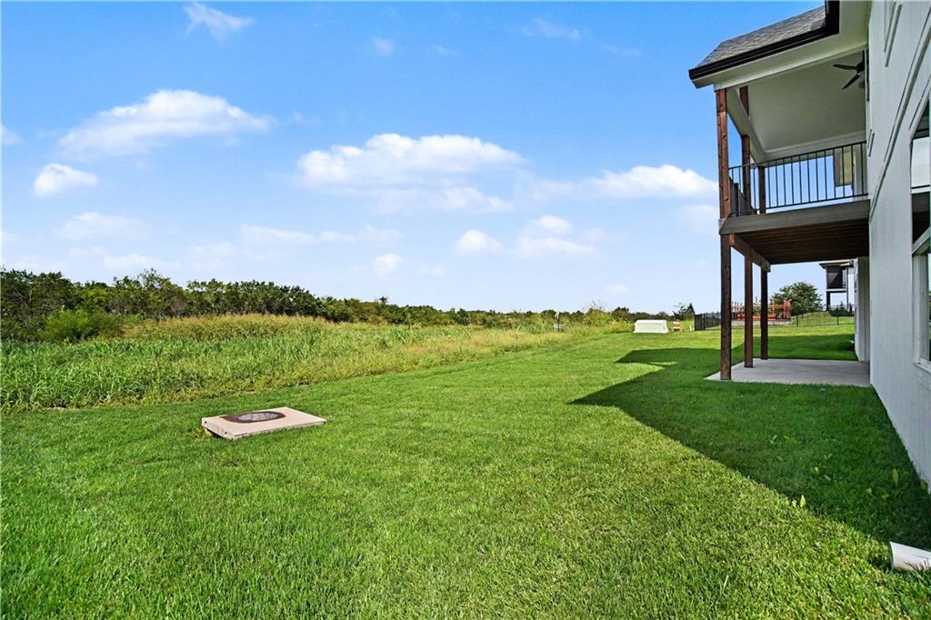 Backyard lawn and raised deck beside the house, with open fields beyond.