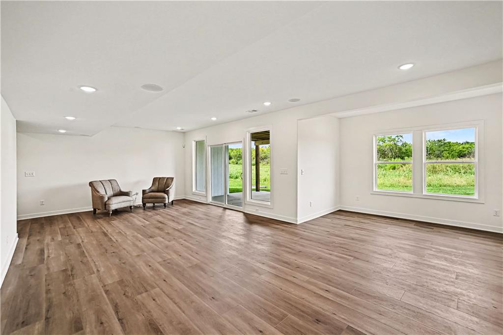 Living room with wood flooring, two armchairs, and sliding glass doors opening to greenery.