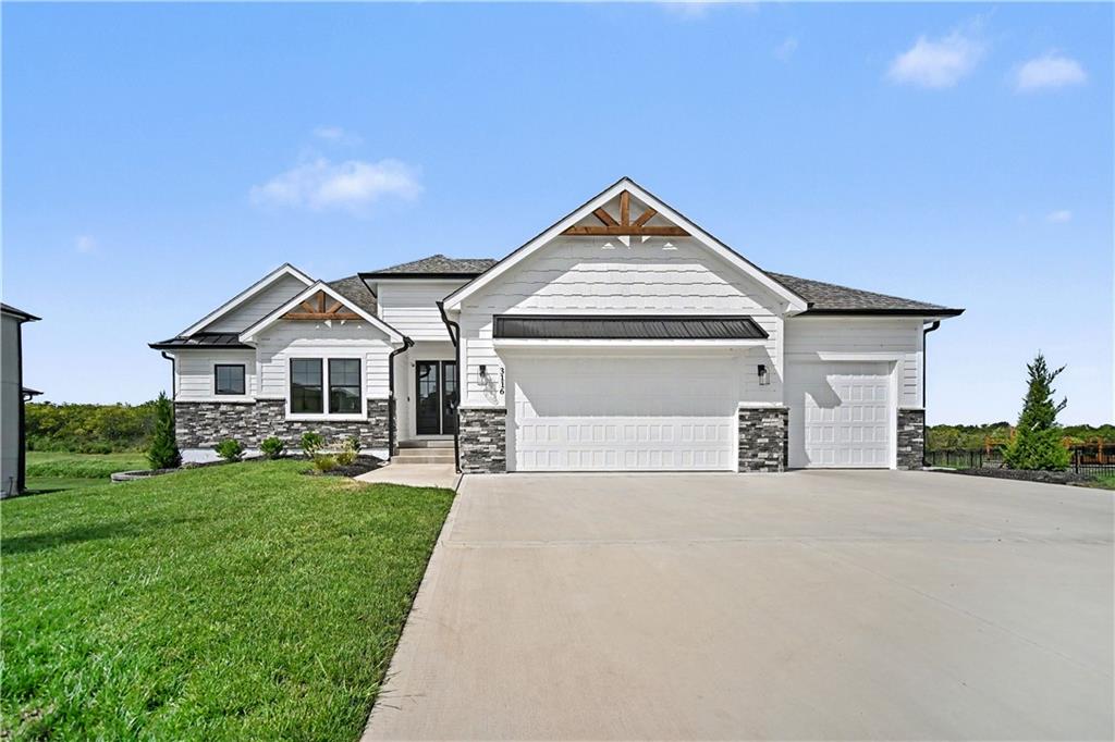 White single-story home with stone accents, three-car garage, and broad concrete driveway.