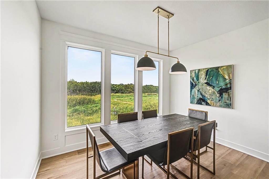 Dining room with a dark table, pendant lights, and tall windows overlooking green fields.