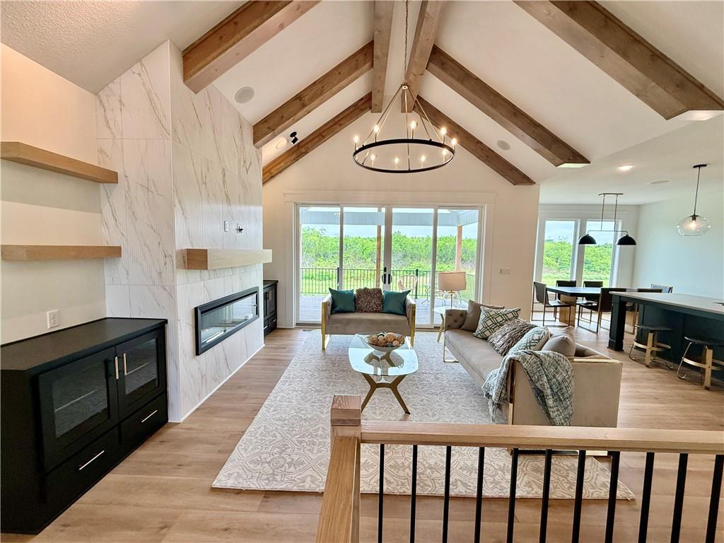 Open living and dining room with vaulted wood-beam ceiling, fireplace, and sliding doors to a deck.
