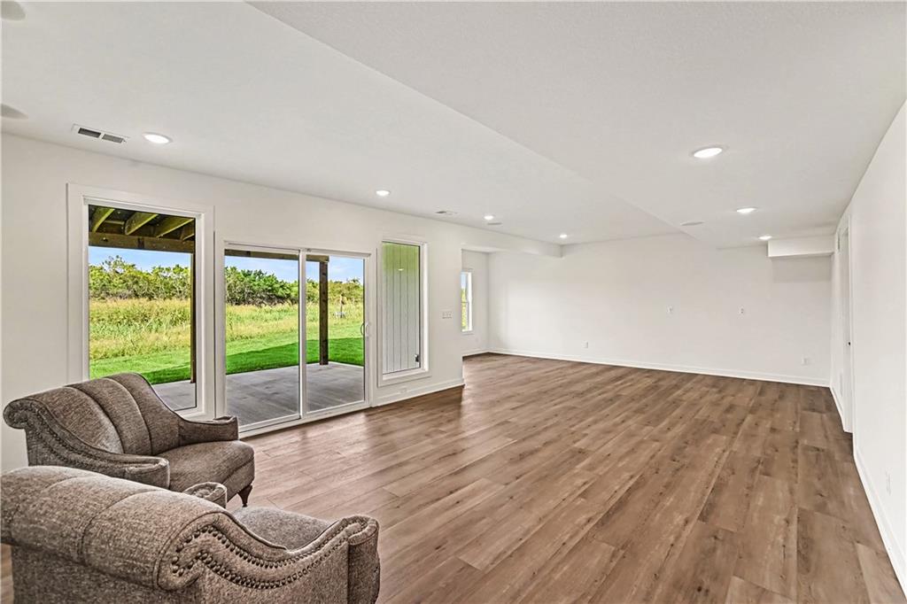 Living room with wood-look floors, upholstered chairs, and sliding glass doors overlooking a grassy yard.