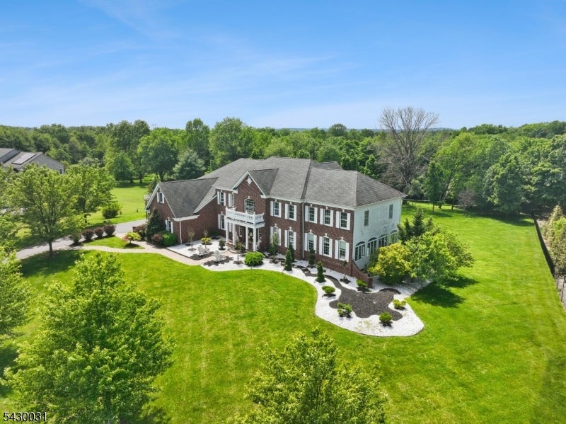 Aerial view of a two-story brick-and-siding home with landscaped grounds and a broad lawn.