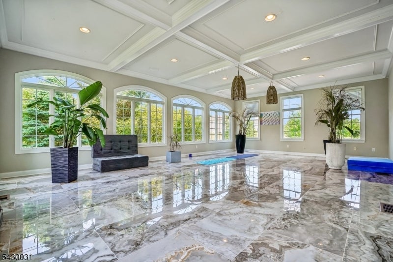 Bright living room with a coffered ceiling, arched windows, and polished marble flooring.