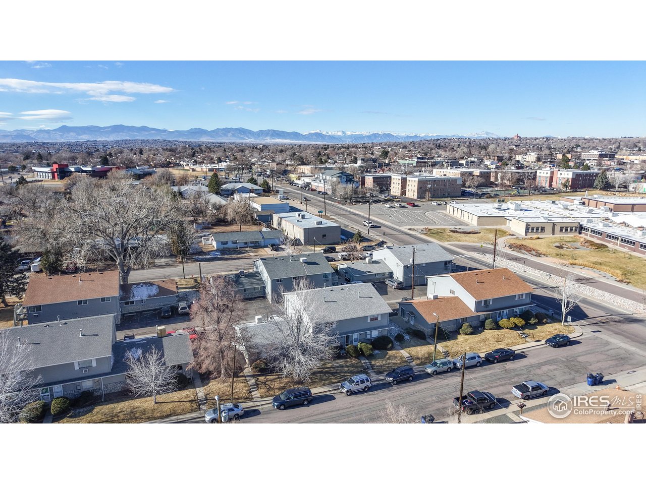 Aerial view of a Denver neighborhood with low-rise homes and the Rocky Mountains on the horizon.