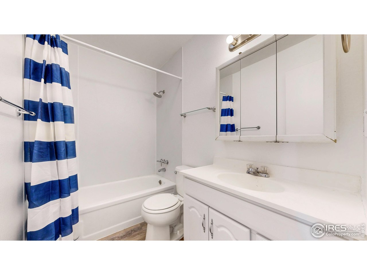 Bathroom with a blue-and-white striped shower curtain, white bathtub, toilet, and vanity.