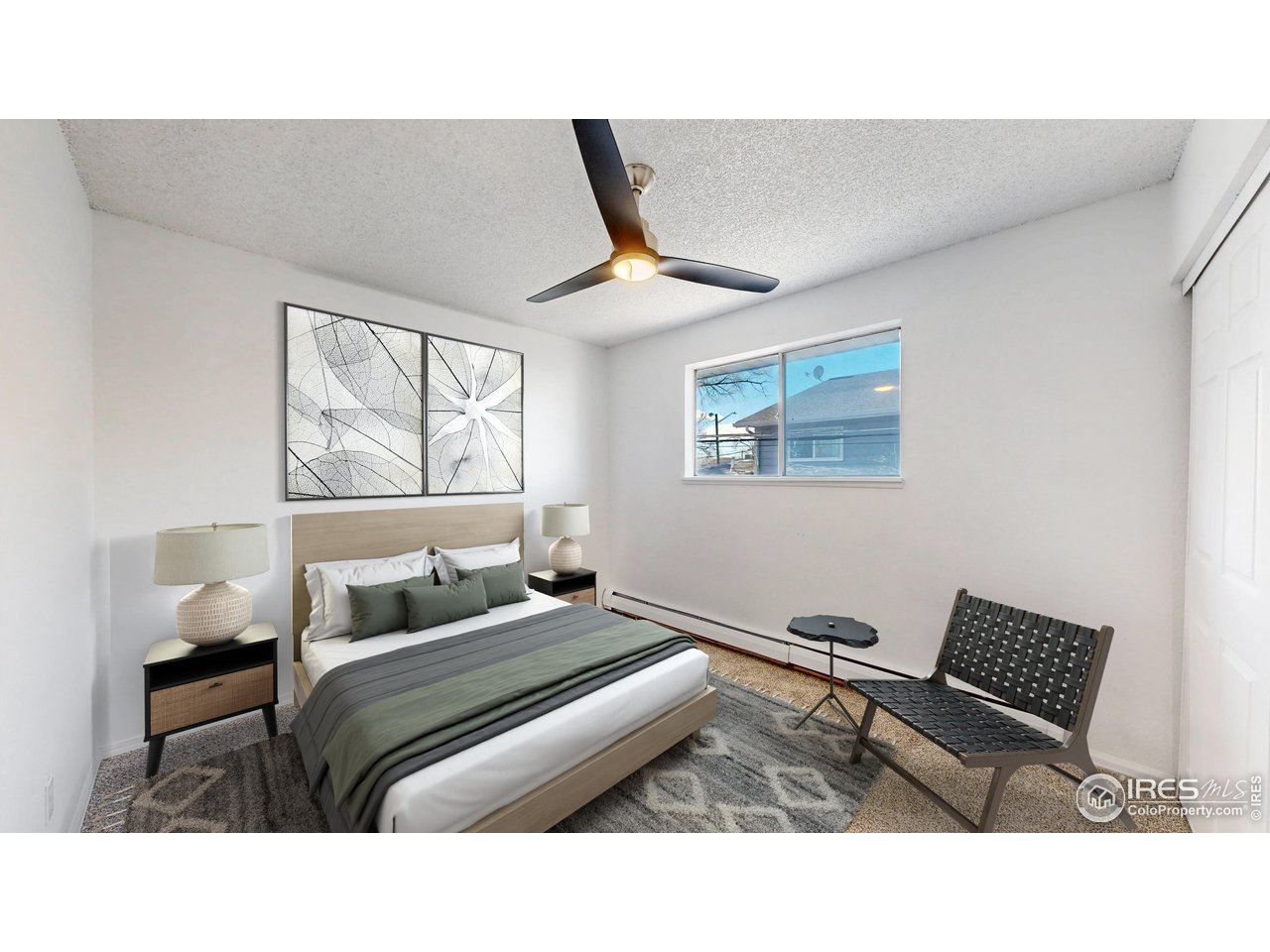 Staged bedroom with a wood-framed bed, green and gray bedding, abstract wall art, and a ceiling fan.