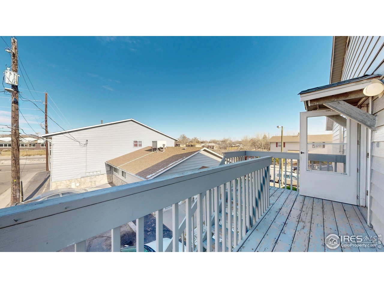 Raised deck with blue-gray railings overlooking neighboring buildings and a street.