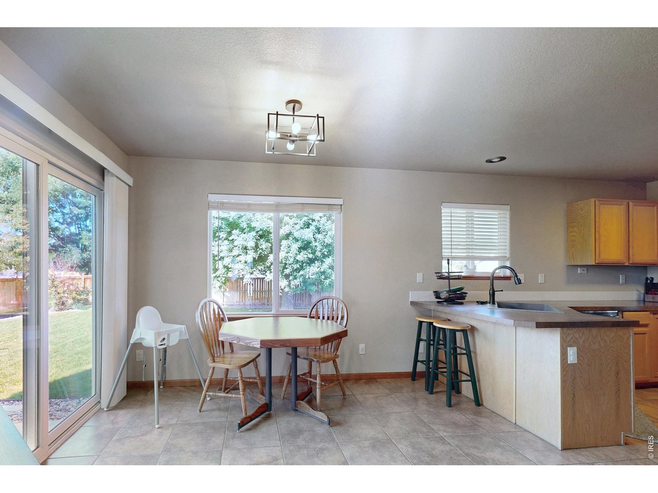 Kitchen and dining area with a peninsula, small table, and large windows overlooking the yard.