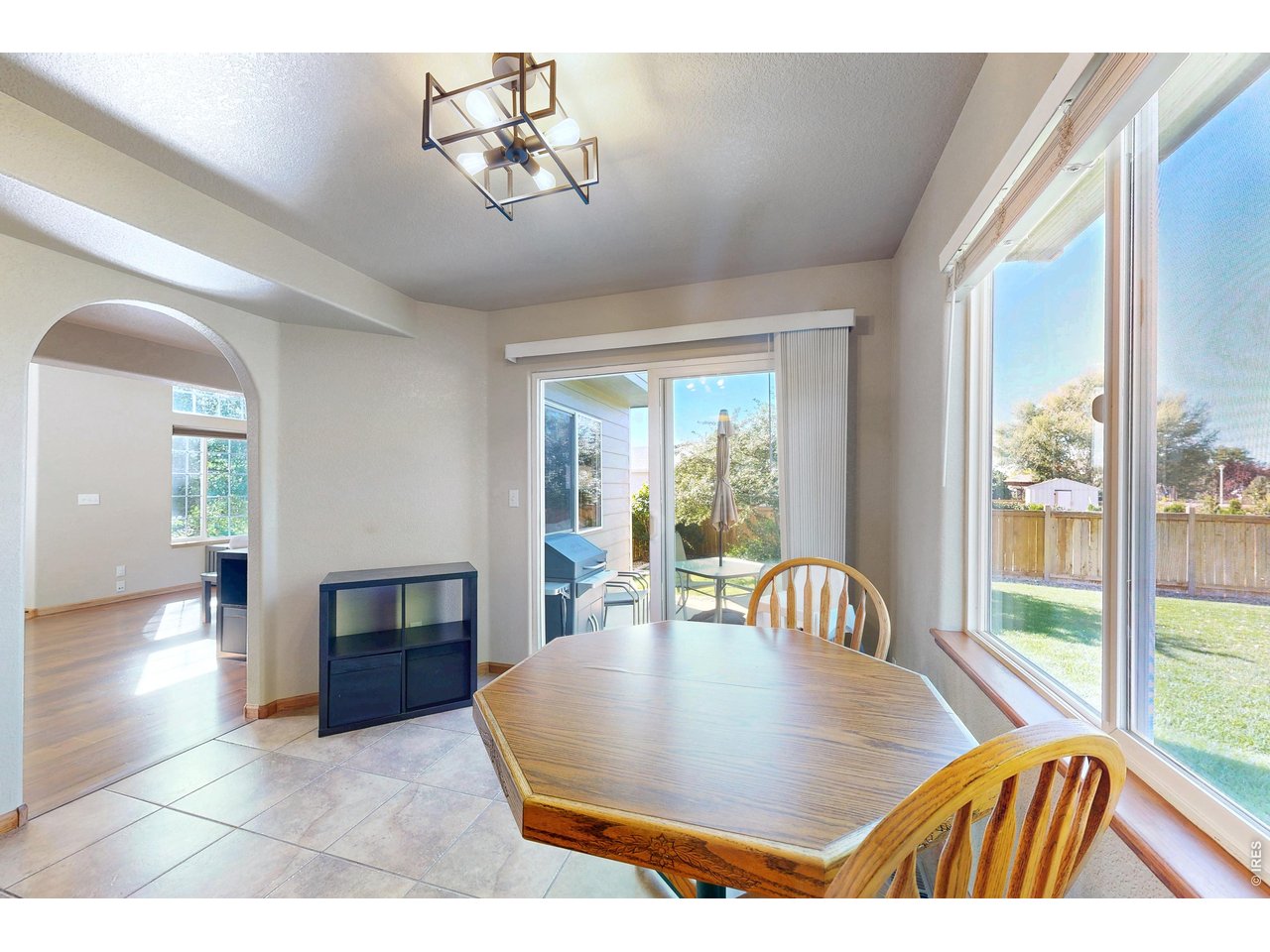 Dining area with a wooden table, large windows, and a sliding glass door opening to the patio.