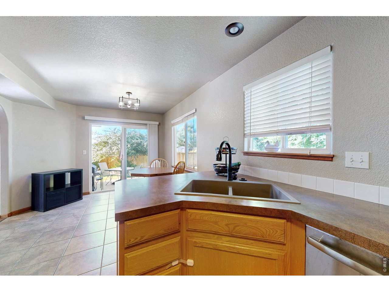 Kitchen peninsula and sink looking toward a dining table and sliding glass doors to the patio.