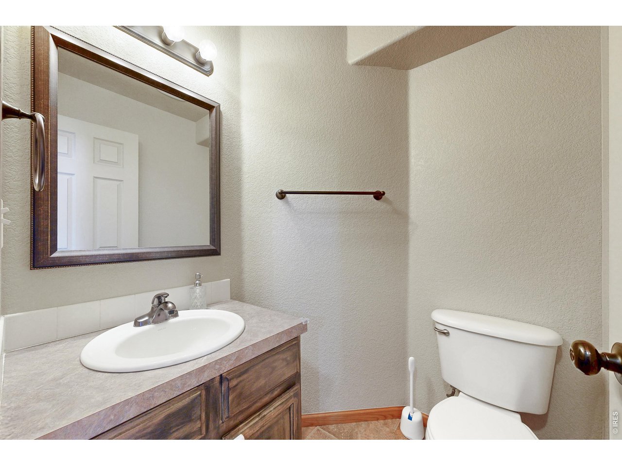 Bathroom with a dark wood vanity, white sink, large framed mirror, and toilet.