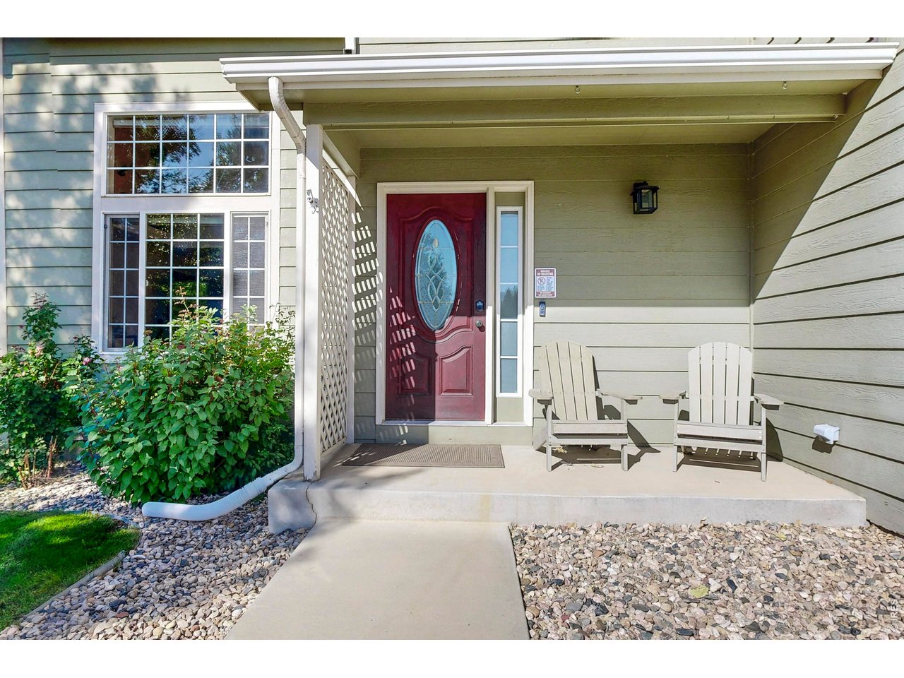 Home entrance with a red glass-paneled door and two white chairs on the covered porch.