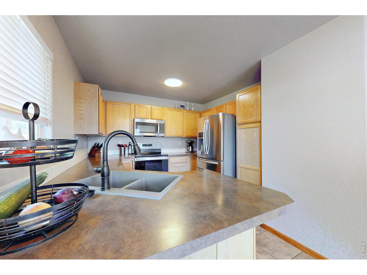 Kitchen with honey-colored cabinets, stainless steel appliances, and a large countertop peninsula.