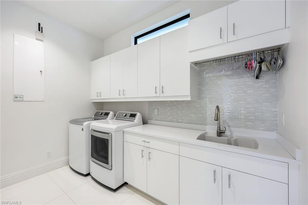 Laundry room with washer and dryer, white built-in cabinets, and a utility sink.