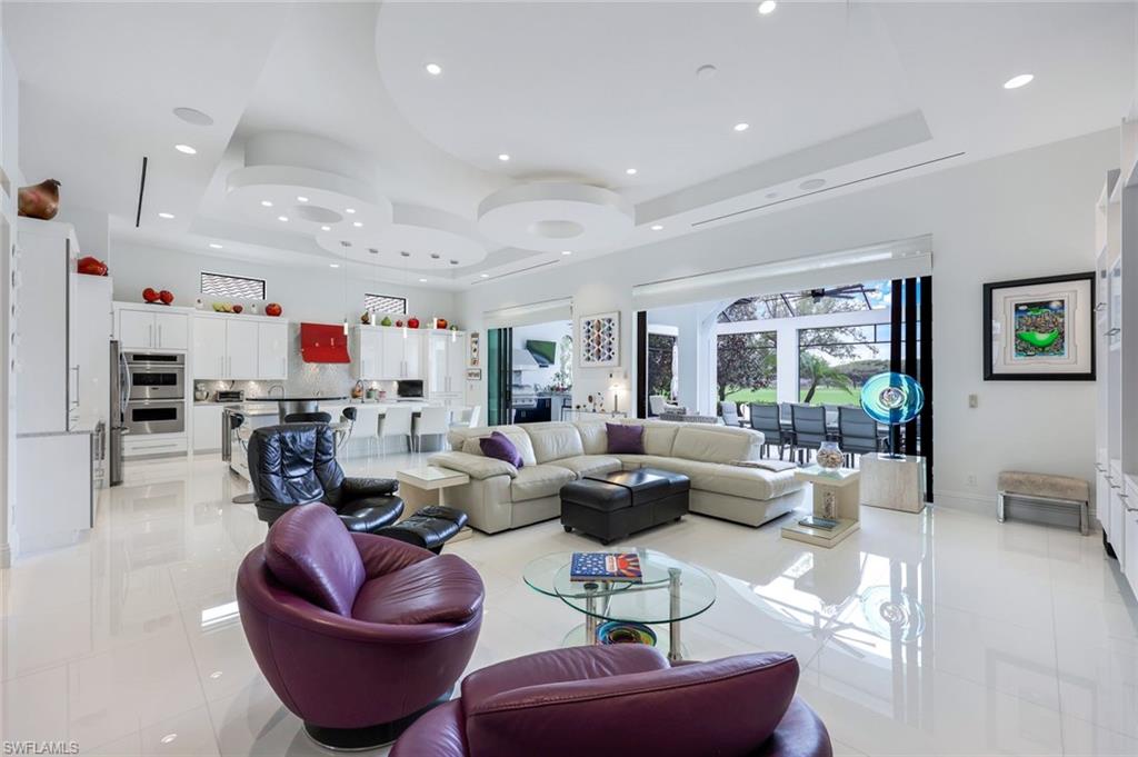 Open-plan living room with a sculptural white ceiling, purple chairs, and glass doors to the patio.