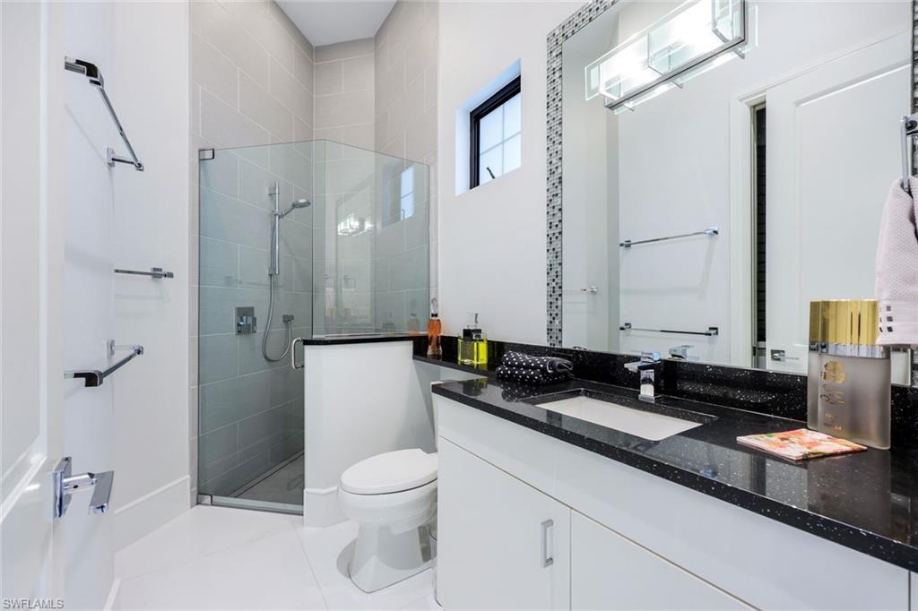 Modern bathroom with a glass shower and white vanity topped with a black countertop.