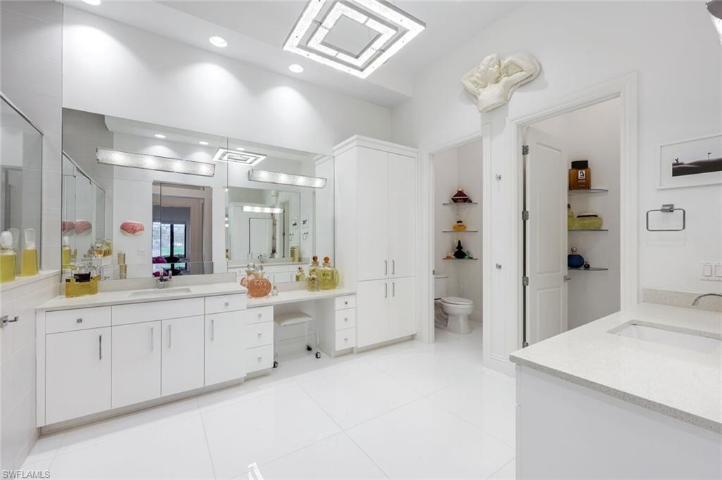 Bright white bathroom with a long vanity, large mirrors, and a separate toilet room.