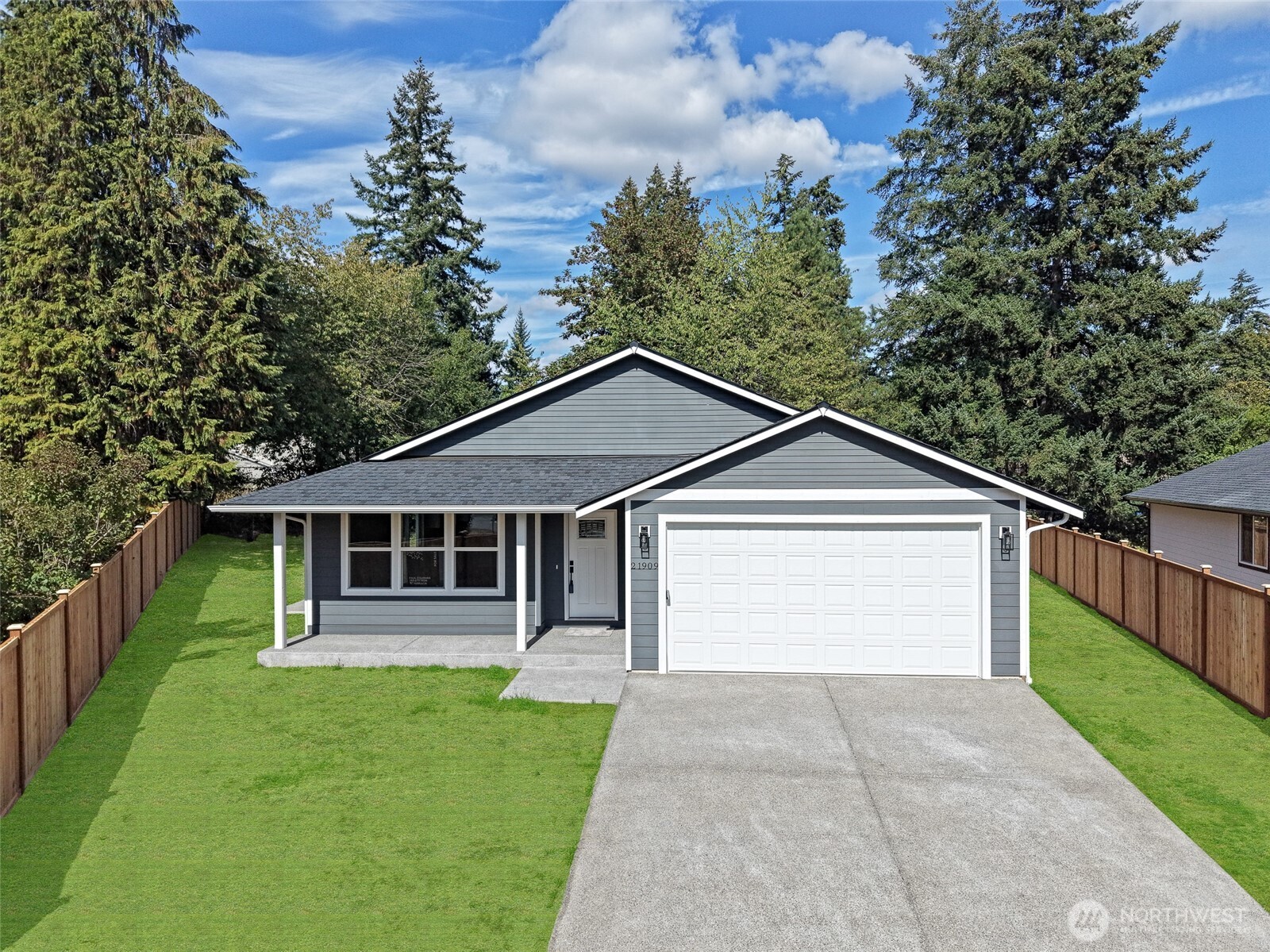 Gray single-story home with a two-car garage, covered porch, and fenced lawn.