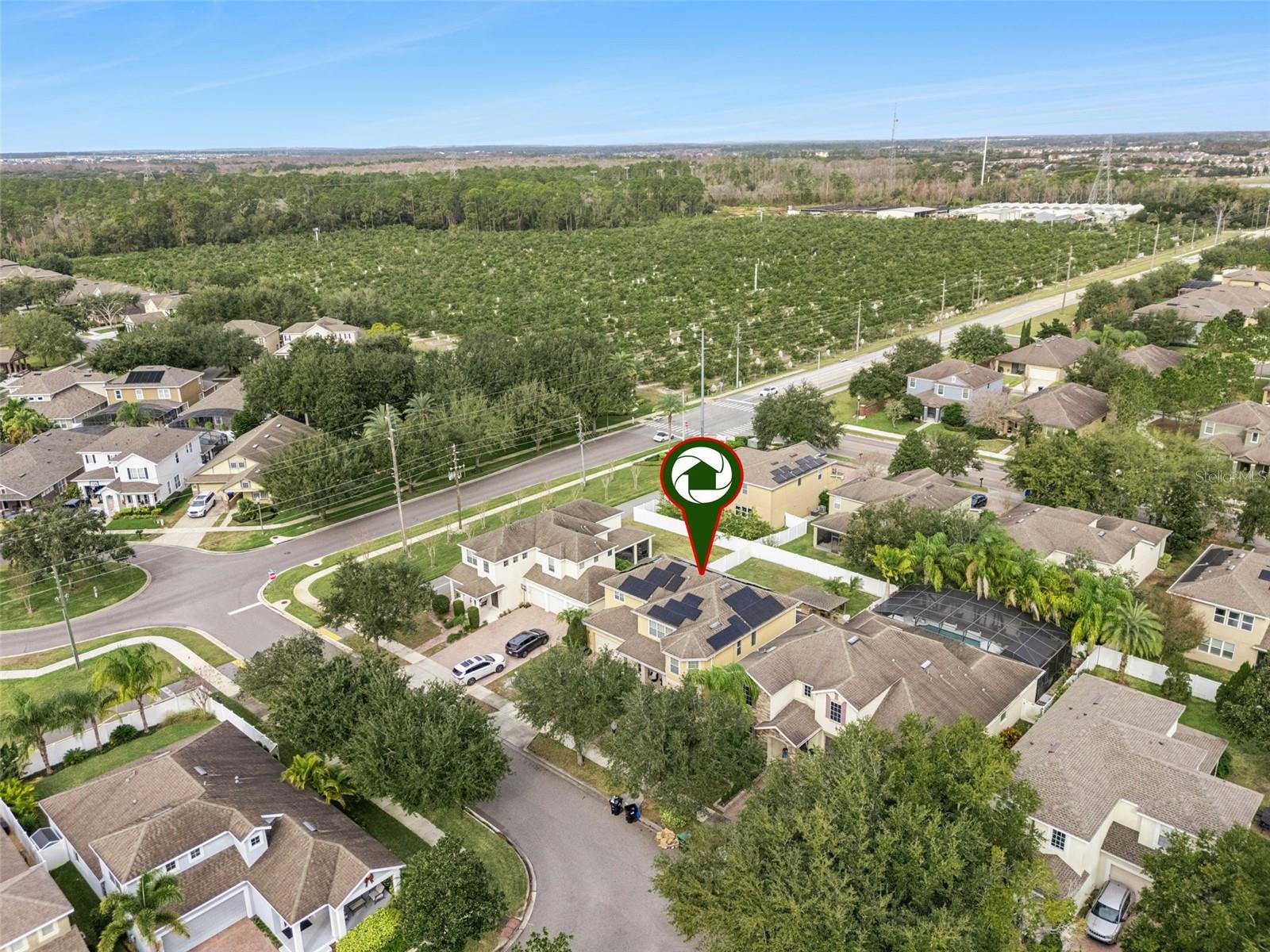 Aerial view of a marked home in a suburban neighborhood beside a large green planted area.