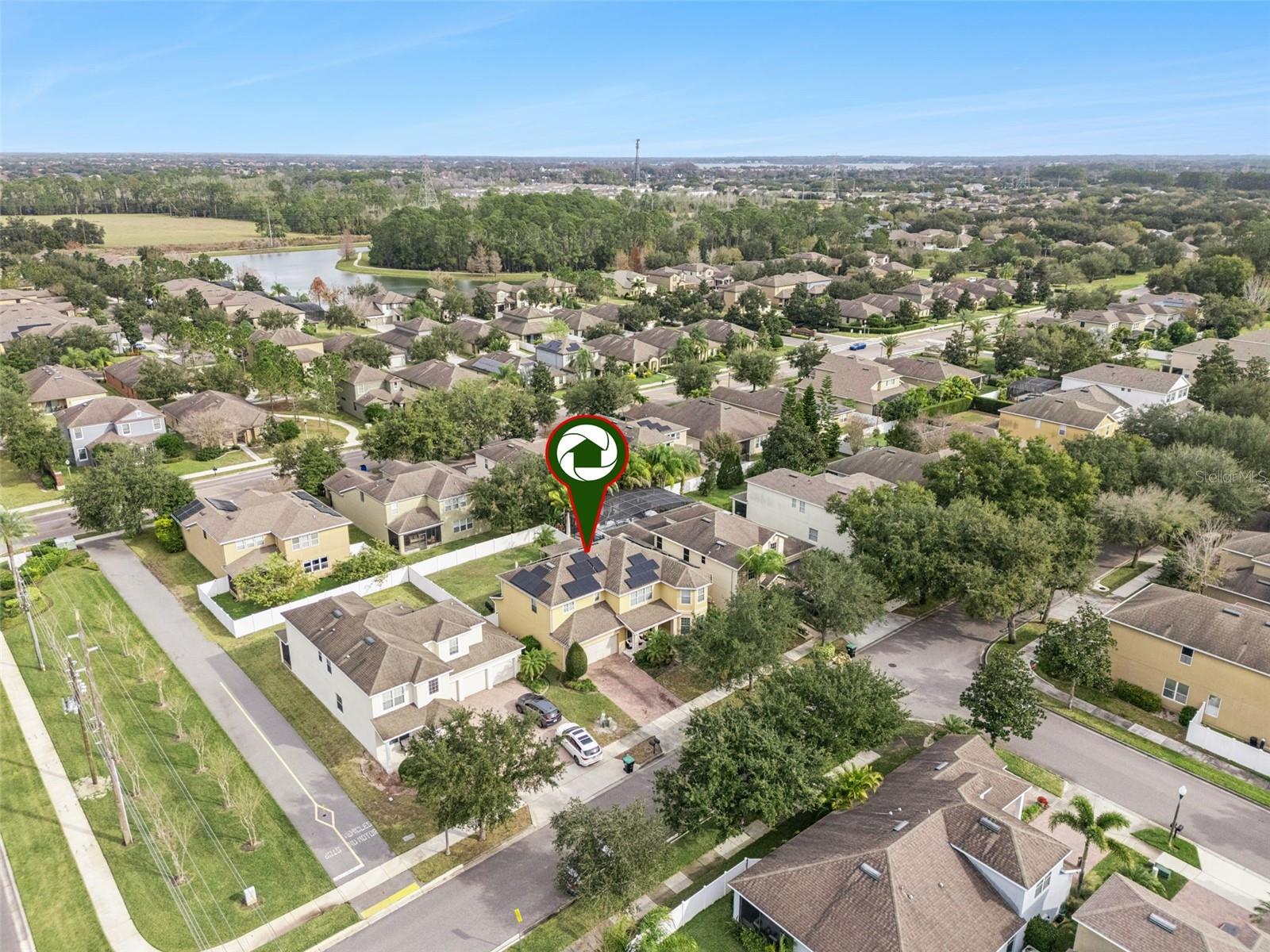 Aerial view of the marked home in a tree-lined neighborhood near a lake.
