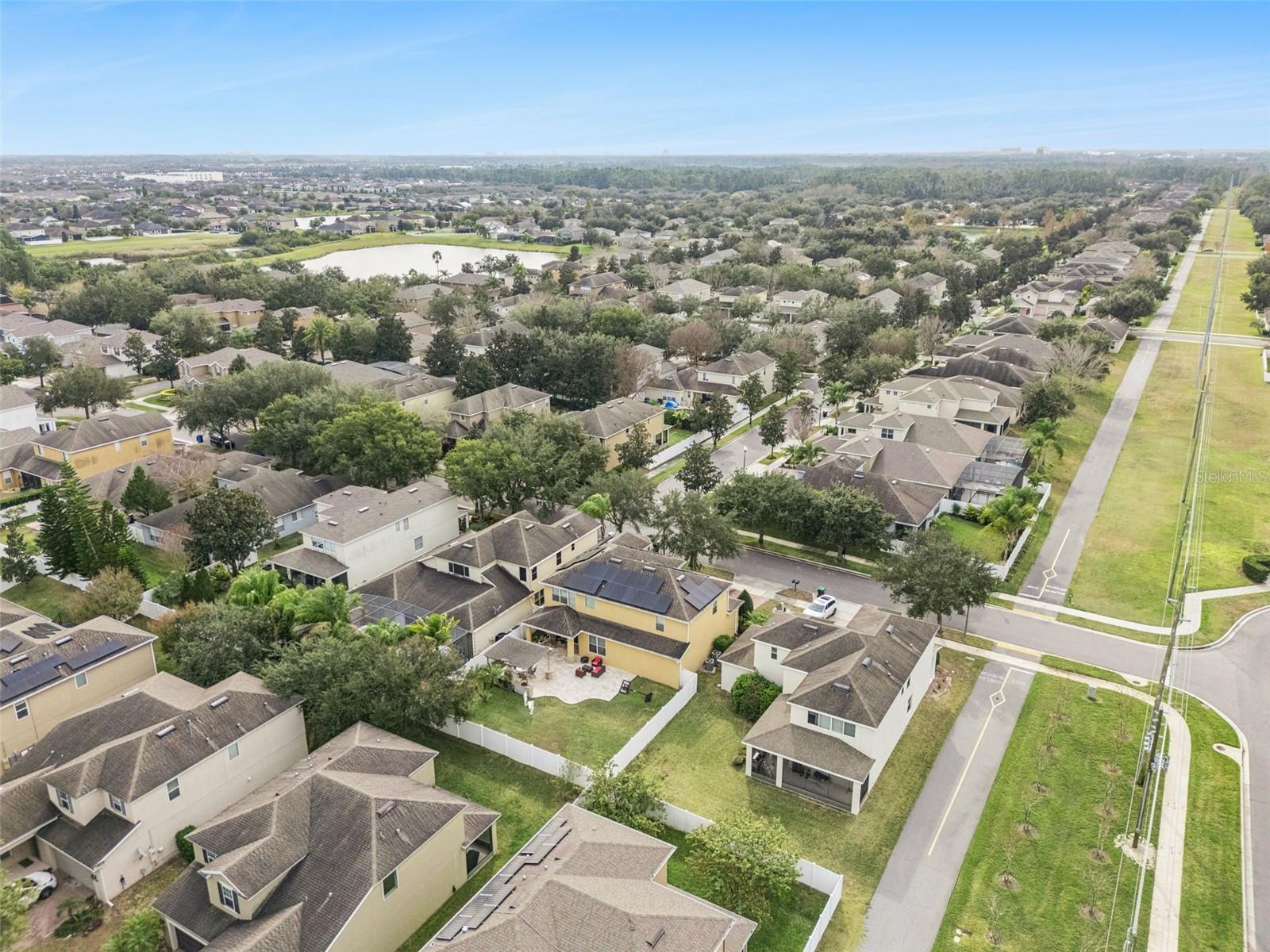 Aerial view of a suburban neighborhood, with a pond and grassy utility corridor.