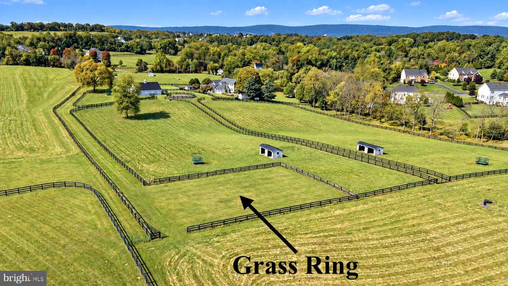 Aerial view of fenced grassy paddocks with sheds and a labeled grass ring.