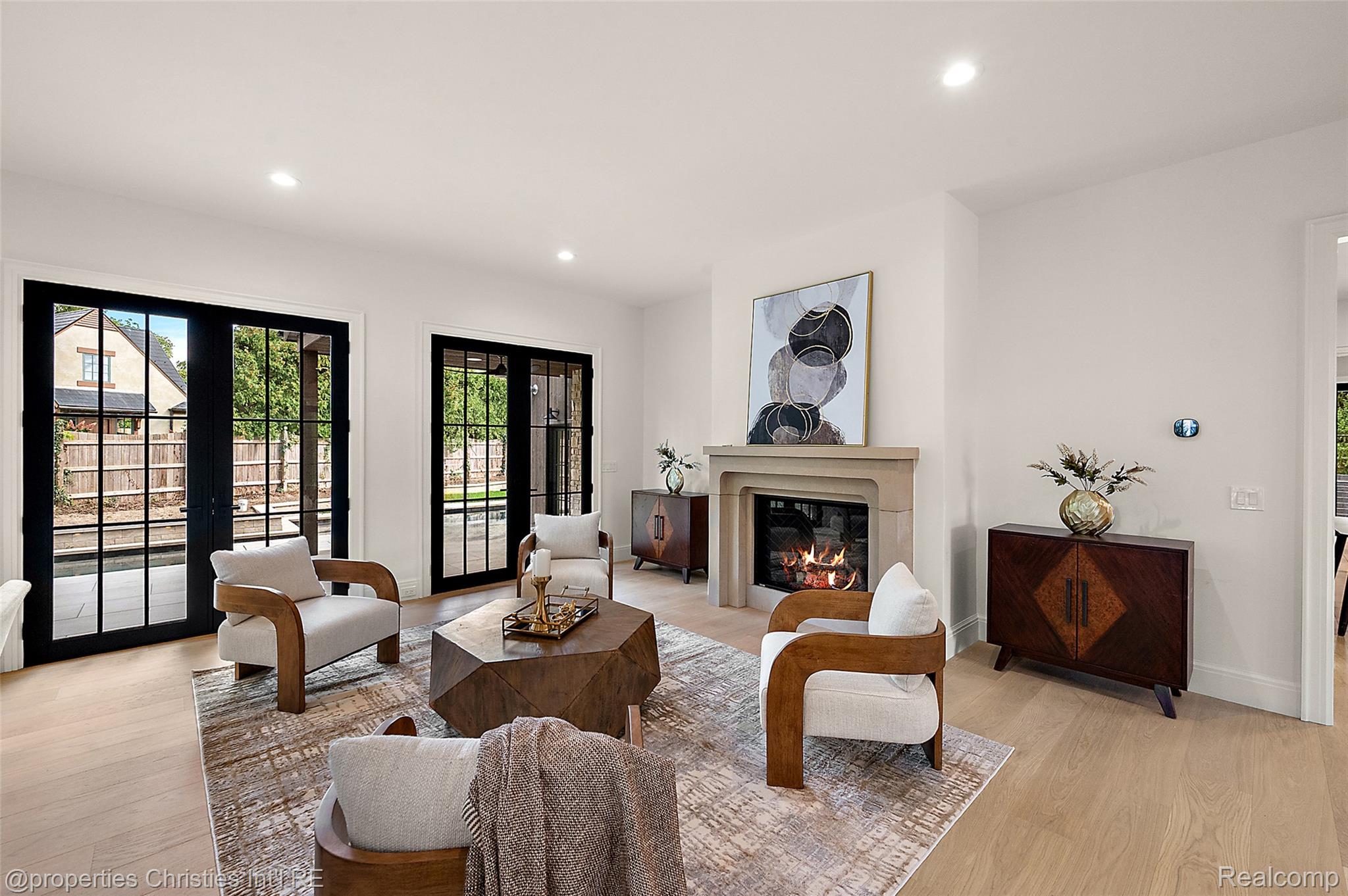 Staged living room with a lit fireplace and black-framed glass doors to the patio.
