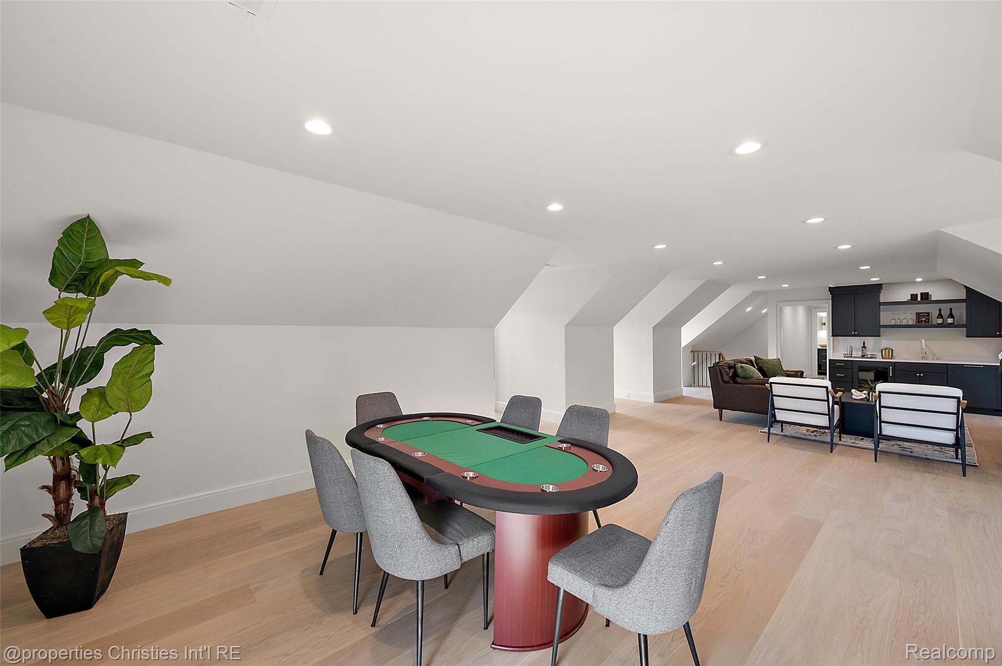 Attic recreation room with a poker table, lounge seating, and dark cabinetry.