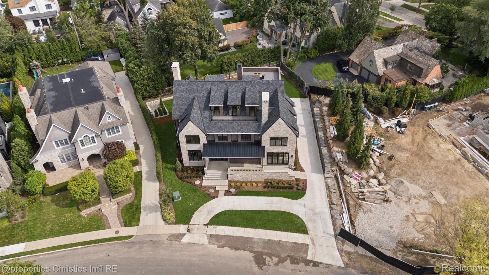 Aerial view of a large stone house with a curved driveway and landscaped front yard.