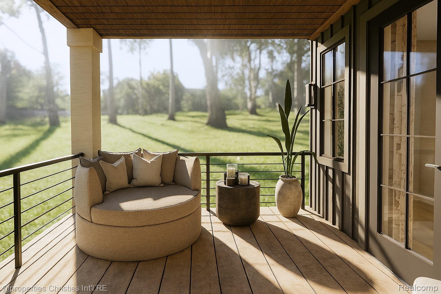 Covered wood deck with a round lounge chair, potted plant, and sunny lawn beyond the railing.