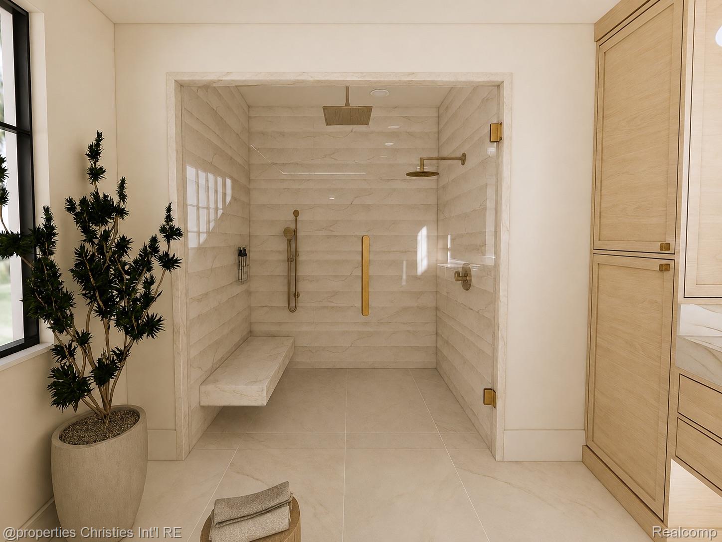 Bathroom with a marble-tiled walk-in shower, built-in bench, brass fixtures, and light wood cabinetry.