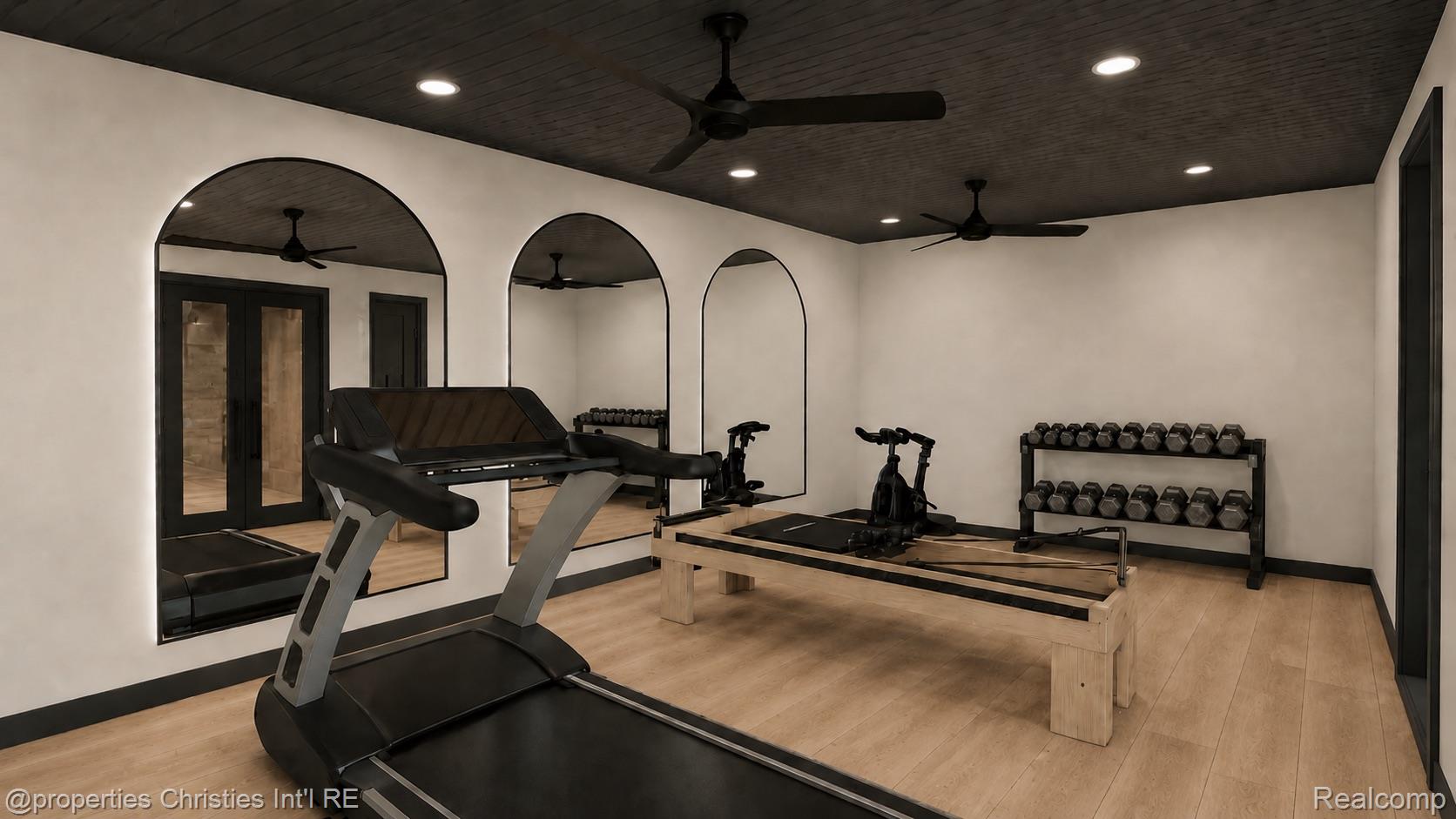 Home gym with treadmill, Pilates reformer, dumbbell rack, and arched mirrors.