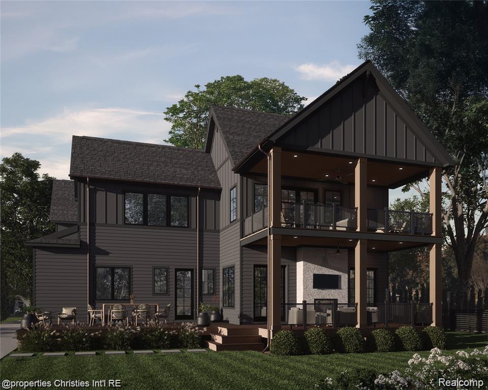 Two-story dark-sided home with steep gables and expansive covered porches overlooking a landscaped lawn.